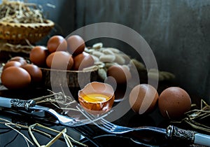 Broken fresh chicken egg Hen egg balanced on a composition of two intertwined forks with fresh chicken eggs on wood background