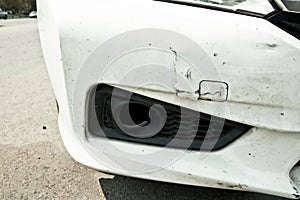 Broken front bumper of white car