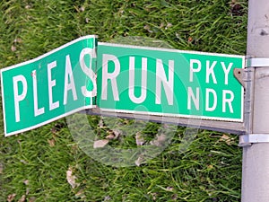 Broken funny road sign bent to look like Please Run or â€œPLEASRUNâ€ lying on the grass