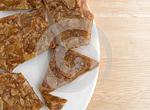 Broken ginger brittle on a plate atop wood table