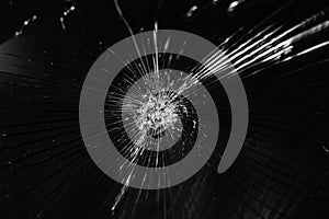 Broken glass background with bullet hole over black background