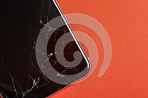 Broken glass of the phone screen. Black mobile phone with a broken screen. Smartphone on a red background close-up. Top view, flat