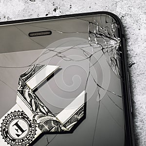 Broken glass on the phone screen and a dollar in the form of a key, as a concept of the cost of repairing a mobile device