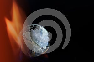 Broken glass planet earth on fire on black background, copy space