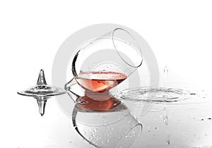 Broken glass with spilled red wine on white background