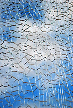 Broken glass texture, blue sky clouds seen thgough it