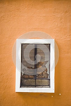 Broken glass in window on orange color plaster cement wall with white frame casing window. Broken or Cracked Window