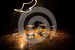 Broken glasses on wooden table at dark toned background with fog. Selective focus