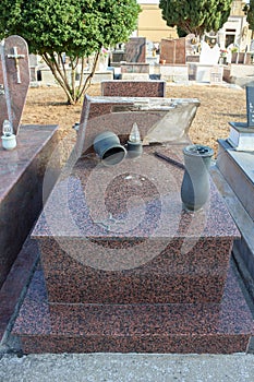 A broken gravestone made of granite, a desecrated grave, a profanation of a cemetery, Italy