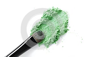 Broken green eye shadow and makeup brush isolated on white background