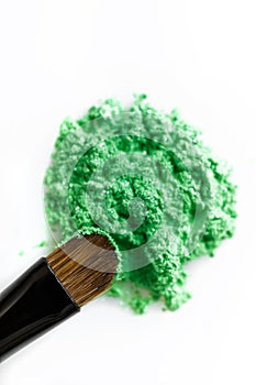 Broken green eye shadow and makeup brush isolated on white background