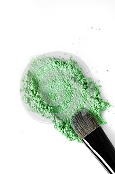 Broken green eye shadow and makeup brush isolated on white background