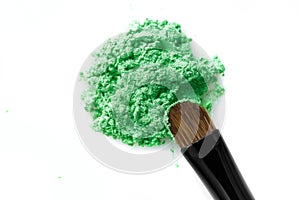 Broken green eye shadow and makeup brush isolated on white background