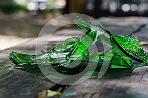 Broken green glass wine bottle on a wooden table in a beach bar.