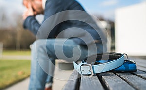 Broken with grief man dog owner is grieving sitting on a bench with the lovely pet collar and deep weeping about animal loss. Home