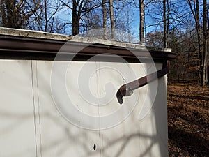Broken gutter downspout on shed in forest or woods