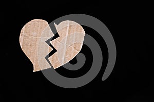 Broken heart with brown paper heart chape on black background. photo