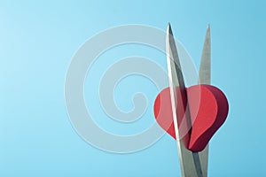 Broken heart cut with scissors on a colored background. Unhappy love, betrayal, quarrel, breakup concept