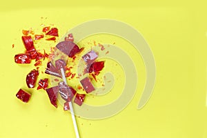 Broken heart red lollipop sweet isolated on yellow background