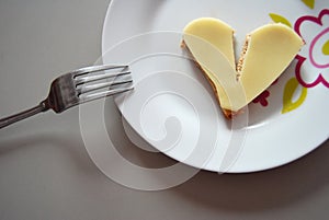 Broken heart shape slice of bread with cheese on a plate