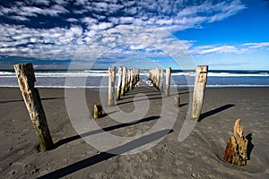 Broken Jetty Looking Out To Sea Old Pilings Left in Sand photo