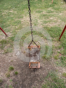 Broken kids swing with metal chain and tube supports on ground front view