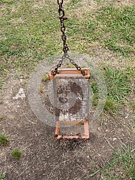 Broken kids swing with metal chain and tube supports on ground front view