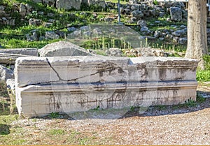 Broken long marble piece of a building carved with Roman letters stacked beside ruins at anicent Corinth near the Temple of Apollo photo