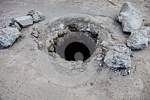 Broken manhole without cover in asphalt surface