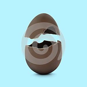 Broken milk chocolate egg on light blue background