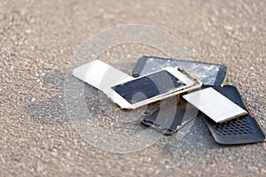 The broken mobile phones are on asphalt.