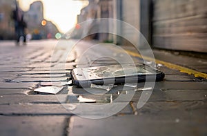 Broken mobile smart phone lies on uneven pavement