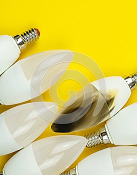 Broken modern LED light bulb after fire, electrical short circuit concept. Home safety. Top view, copy space, yellow