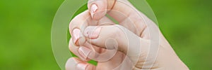 Broken nail on a woman`s hand with a manicure on a green background BANNER, LONG FORMAT