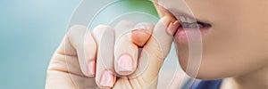 Broken nail on a woman`s hand with a manicure on a green background. Woman bites nails BANNER, LONG FORMAT