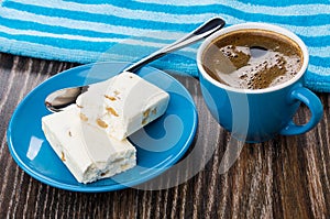 Broken nougat, spoon in saucer, blue napkin, coffee in cup