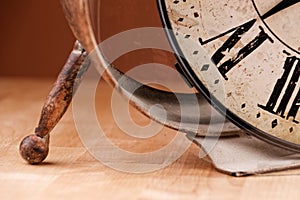 Broken old analog clock with glass and metal frame on wooden table, broken structure