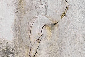 Broken old crack on the surface of a white cement dirty wall damaged concrete background