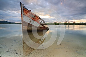 Broken and old fishing boat with the sunset moment