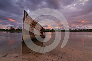 Broken and old fishing boat with the sunset moment