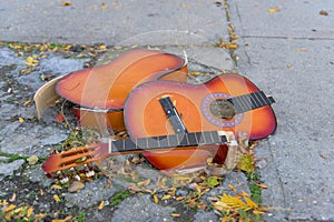 Broken old guitar lying on the concrete, discarded on a New York City street