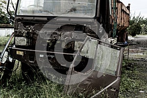 Broken old truck that has been badly damaged abandoned in the middle of a park in the midday