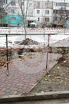 Broken paving slabs, metal fencing and protective construction tape