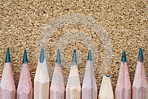 Broken pencil tip beside of other sharp ones on particle board texture background with copy space