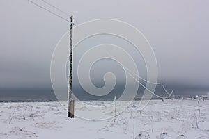 Broken phase electrical power lines with hoarfrost on the wooden electric poles on countryside in the winter after storm