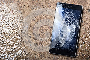 Broken Phone with cracked screen on wet concrete