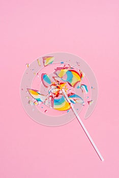 Broken in pieces Colorful lollipop on pastel pink background, top view. Candy colours. Minimal Sugar detox and junk food