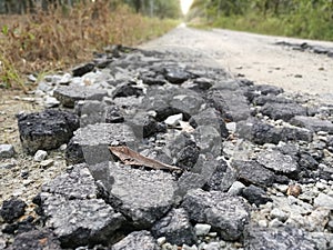 Broken pieces of tarmac stone on the rural road