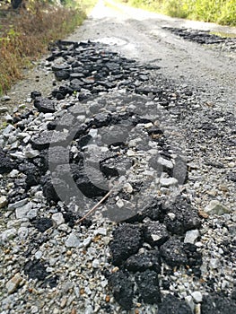 Broken pieces of tarmac stone on the rural road