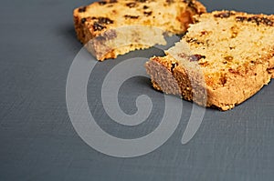 Broken pieces of tasty sweet homemade bread with raisin lies on dark concrete table in kitchen